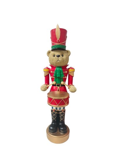 Christmas nutcracker bear dressed as a nutcracker drummer in a red uniform with a green scarf, standing with a decorative drum and tall ceremonial hat.
